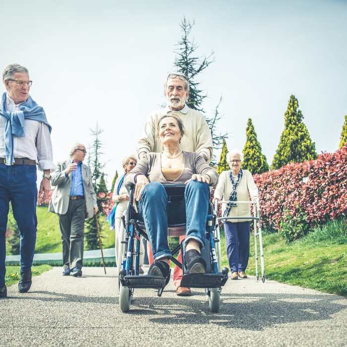 Group of senior people with some diseases walking outdoors - Mature group of friends spending time together