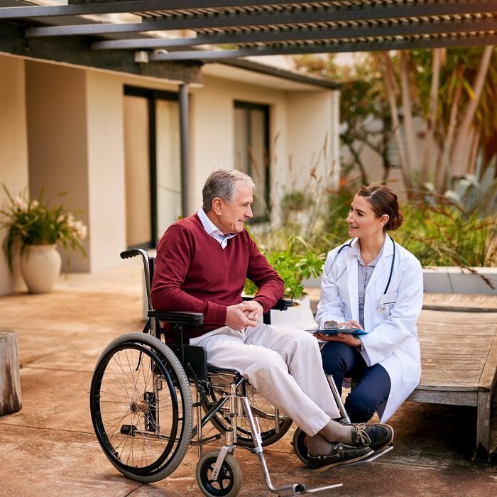 Shot of a young doctor and her elderly patient talking while sitting outside.
