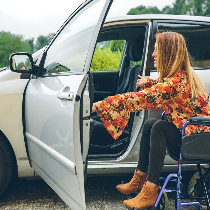 Young woman in a wheelchair getting on the car